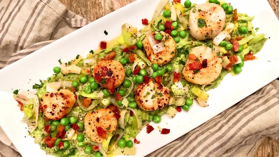 Treat yourself to a flavorful seafood feast with our scallops with corn, peas, and bacon recipe. The succulent scallops pair perfectly with the sweet corn, tender peas, and crispy bacon for a dish that's sure to impress.